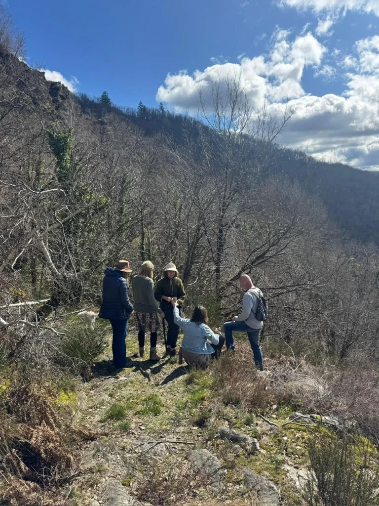 Een groep bezoekers wandelt samen door het bosrijke natuurgebied van Domaine du Puech Fleuri in de Vallée du Lot, Frankrijk, met uitzicht op de heuvels van de Châtaigneraie Cantalienne.